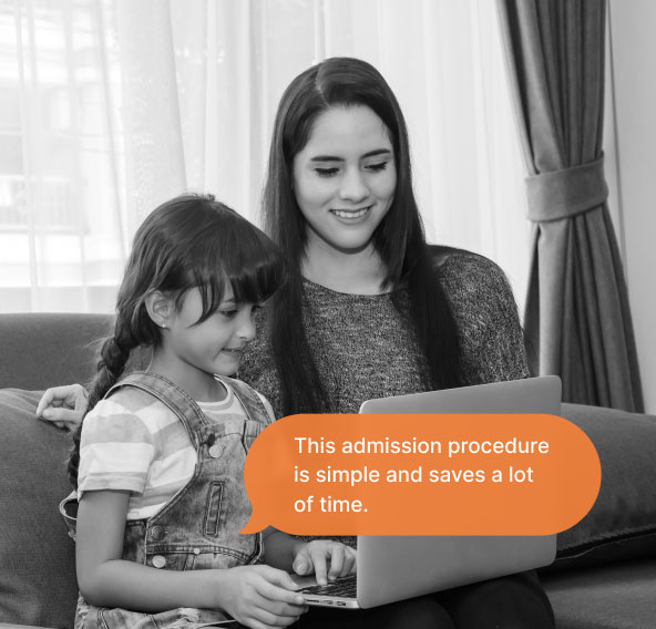 A woman and her daughter sitting on a couch looking at the laptop