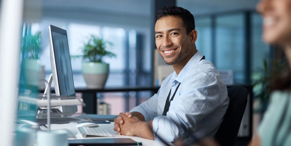 A school admin sitting at his desk looking at the camera smiling